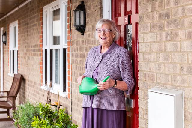 ELderly person outside holding a watering can