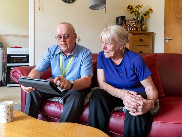 Staff member sat on sofa chatting to tenant