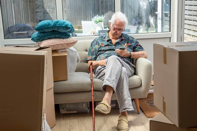 Person sitting on sofa surrounded by boxes
