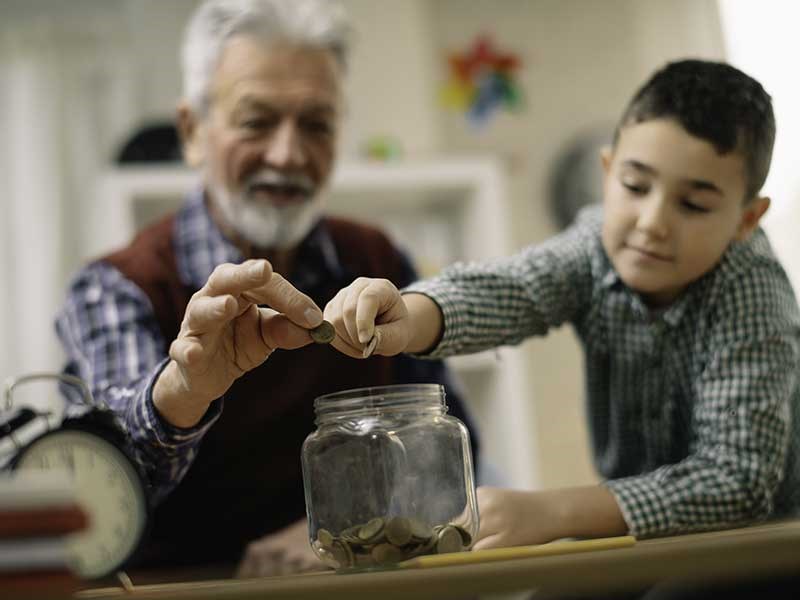 Image of man and boy putting money in jar
